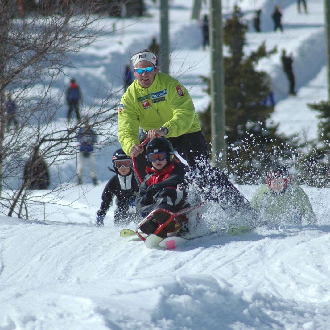 Barn kjører ski i alpinanlegg med voksen fører