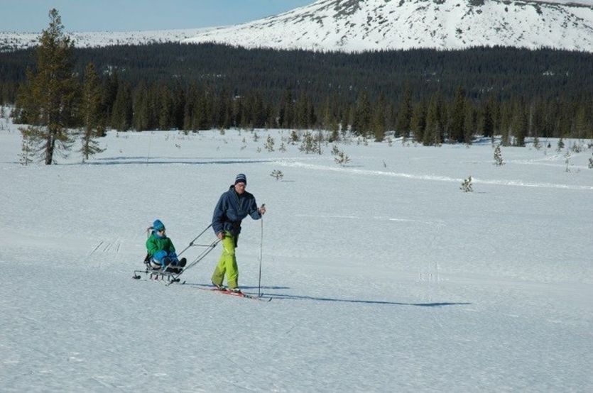 Mann på ski drar barn på utstyr fra Sitski Norway